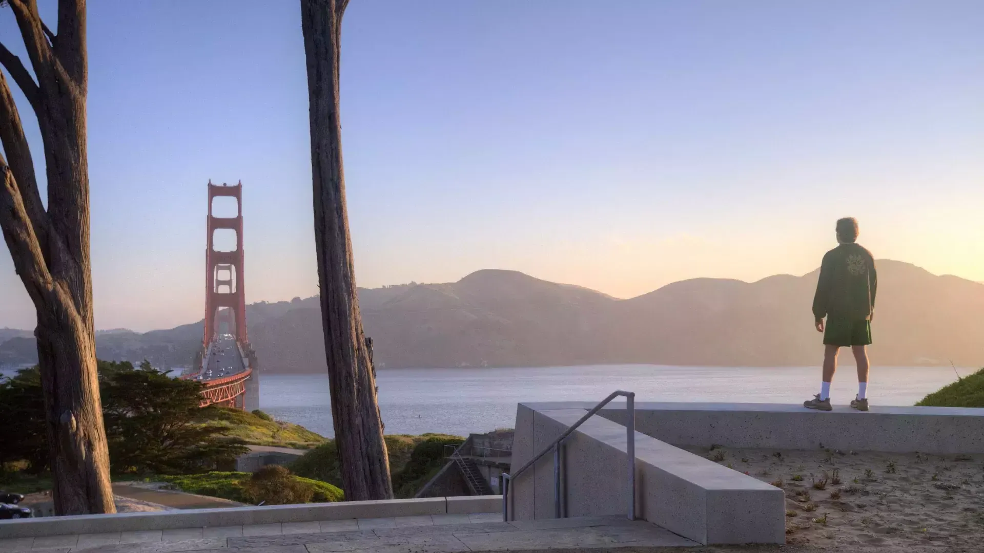 Un hombre contempla el Golden Gate Bridge con montañas al fondo.