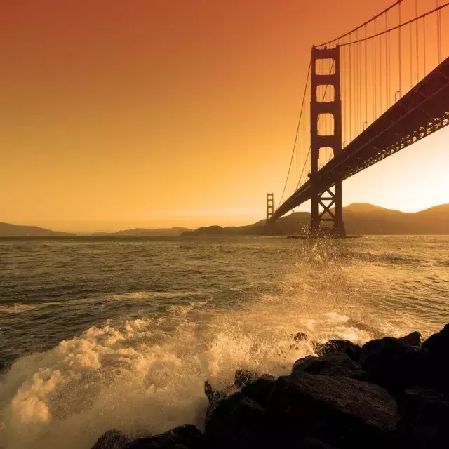 Las olas se estrellan cerca de Fort Point, debajo del Golden Gate Bridge al sunset .